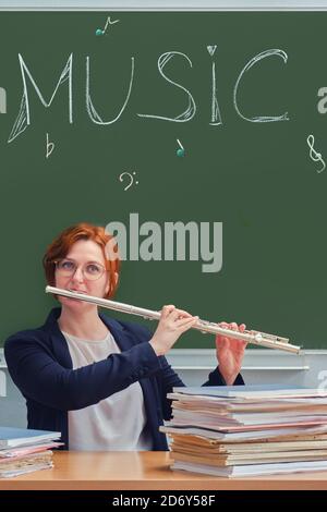 Frau Musiklehrerin spielt Flöte in der Schulklasse Stockfoto