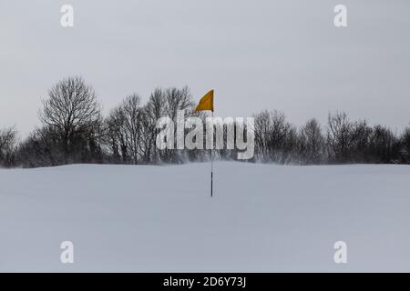 Gelbe Flagge auf einem schneebedeckten Golfplatz Stockfoto