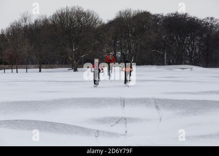 Drei Jungs auf Mountainbikes auf einer schneebedeckten Landschaft Stockfoto