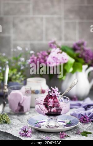 Tasse köstliche hausgemachte Heidelbeer-Eis und Flieder auf dem Hintergrund Stockfoto