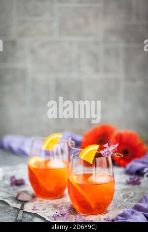 Orange Aperol Spritz Cocktail in einem Weinglas serviert, dekoriert mit einer Scheibe Orange und Flieder Stockfoto