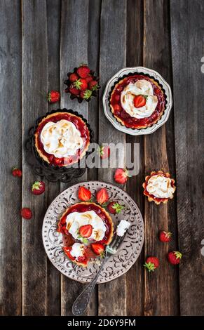 Erdbeer-Meringue-Tartlets auf rustikalem Holzhintergrund Stockfoto