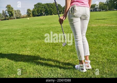 Golferin auf dem grünen Gras stehend Stockfoto