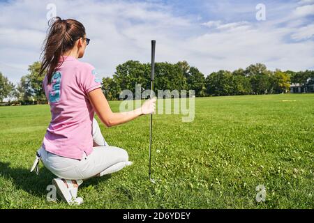 Kaukasische Golferin mit einem Pferdeschwanz auf ihren Spukken sitzend Stockfoto
