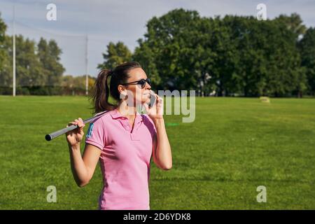 Attraktive Golfspieler mit ihrem Gadget draußen Stockfoto