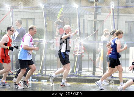 Läufer kühlen sich bei der 20.5-Meilen-Marke des London Marathon 2011 in den Docklands im Osten Londons unter Wasserschauern ab. Stockfoto