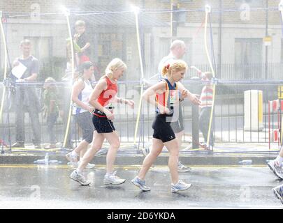 Läufer kühlen sich bei der 20.5-Meilen-Marke des London Marathon 2011 in den Docklands im Osten Londons unter Wasserschauern ab. Stockfoto