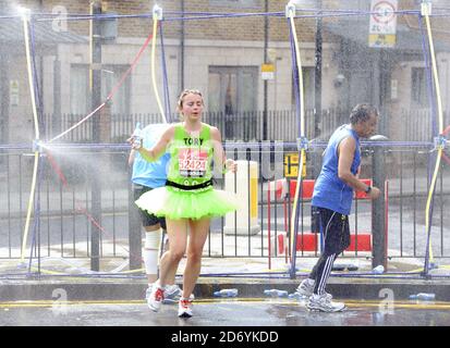 Läufer kühlen sich bei der 20.5-Meilen-Marke des London Marathon 2011 in den Docklands im Osten Londons unter Wasserschauern ab. Stockfoto