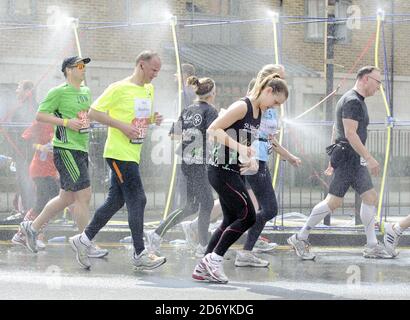 Läufer kühlen sich bei der 20.5-Meilen-Marke des London Marathon 2011 in den Docklands im Osten Londons unter Wasserschauern ab. Stockfoto