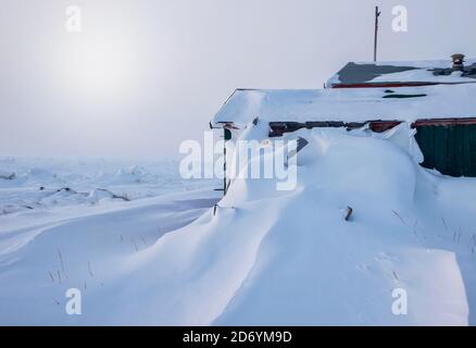 Nach einem Wintersturm in Churchill, Manitoba, Kanada, stapelten sich tiefe Schneeverwehungen gegen die Seite eines Hauses. Stockfoto