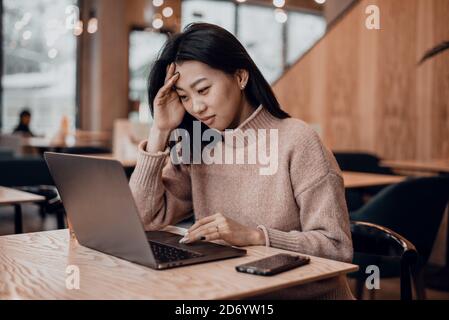 Das peinliche Mädchen arbeitet in einem Laptop in einem Café und ist mit den Fehlern unzufrieden. Verwirrte Geschäftsfrau ärgert sich über Online-Problem, Spam-E-Mail oder gefälschte Internet-Nachrichten auf dem Laptop. Arbeitsantin fühlt sich schockiert über festgefahrenen Computer, verwirrt durch Betrug oder Virus. Stockfoto