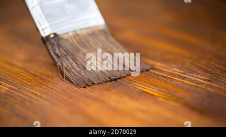 Nahaufnahme des Pinsels mit brauner Farbe auf Holztisch. Stockfoto