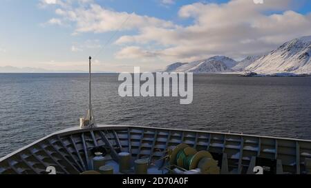 Sørøysundet, Norwegen - 03/02/2019: Bug des Hurtigruten Kreuzfahrtschiffes MS Trollfjord im arktischen Meer in der Nähe der Insel Sørøya mit schneebedeckten Bergen. Stockfoto
