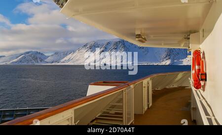 Sørøysundet, Norwegen - 03/02/2019: Küste der Insel Sørøya mit schneebedeckten Bergen im Winter von der Nase des Hurtigruten Kreuzfahrtschiffes aus gesehen. Stockfoto