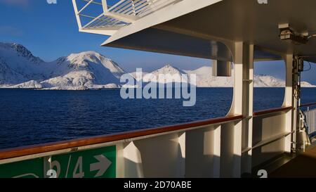 Sørøysundet, Norwegen - 03/02/2019: Schneebedeckte Berge der arktischen Insel Sørøya im Winter vom Deck des Hurtigruten Kreuzfahrtschiffes beobachtet. Stockfoto