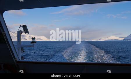 Sørøysundet, Norwegen - 03/02/2019: Blick auf den arktischen Ozean in Nordnorwegen mit schneebedeckten Bergen vom Heck des Hurtigruten Kreuzfahrtschiffes. Stockfoto