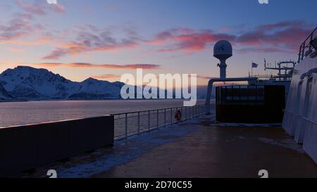 Sørøysundet, Norwegen - 03/02/2019: Oberdeck des Hurtigruten Kreuzfahrtschiffes MS Trollfjord mit orangefarbenen Wolken im Abendlicht. Stockfoto