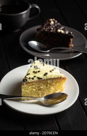 Stück Zitrone und Schokoladenkuchen auf Dessertplatte auf schwarzem Tisch. Stockfoto