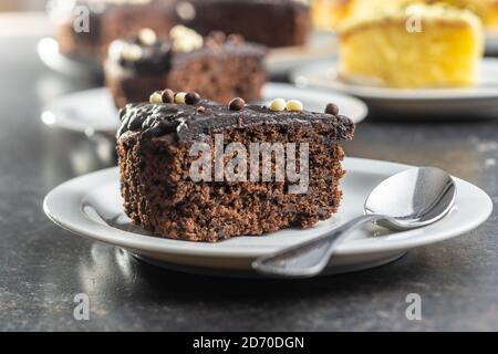 Stück Schokoladenkuchen auf Dessertplatte auf schwarzem Tisch. Stockfoto