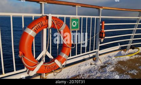 Sørøysundet, Norwegen - 03/02/2019: Orangefarbener Rettungsgürtel mit dem Schiffsnamen, der an der Reling des Oberdecks des Hurtigruten Kreuzfahrtschiffes montiert ist. Stockfoto