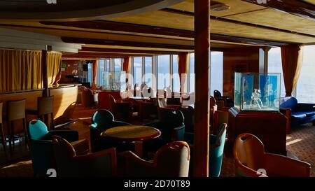 Sørøysundet, Norwegen - 03/02/2019: Innenarchitektur einer Bar auf dem Hurtigruten Kreuzfahrtschiff (RoRo Fähre) MS Trollfjord mit Stühlen, Tischen und Dekoration. Stockfoto