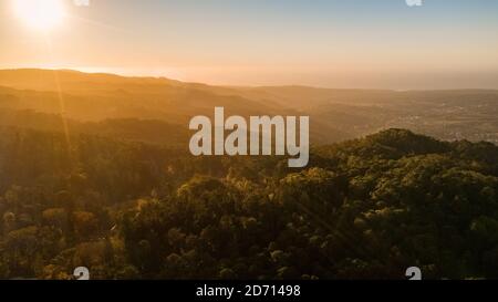 Sonnenuntergang oder Sonnenaufgang über wilden Waldbergen. Luftgipfel mit Sonnenlicht Stockfoto