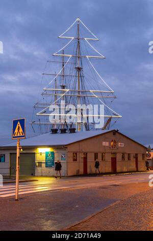 Bergen, Norwegen - 12. Dezember 2015: Blick auf das Hafengebäude, im Hintergrund die Lichter in Form eines Weihnachtsbaums auf dem Segelschiff. Vagen Stockfoto