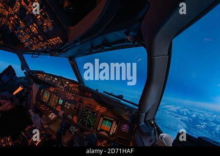 Flight Deck des modernen Passagierflugzeugs, Piloten Blick in Kreuzfahrt während der blauen Stunde. Schönes Licht bei Sonnenuntergang aus einem Jet-Flugzeug-Cockpit Stockfoto