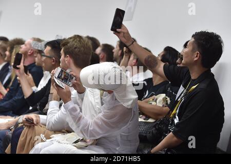 Die Gäste fotografieren auf ihrem Handy bei der Kit Neale Modenschau während der London Collections: Men des British Fashion Council im Old Sorting Office in London. Stockfoto