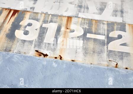 Zahlen und japanischer Text auf teilweise rostiger Metalloberfläche Stockfoto