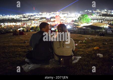 Festivalbesucher bewundern den Blick spät in die Nacht beim Glastonbury Festival, auf der Worthy Farm in Somerset. Stockfoto