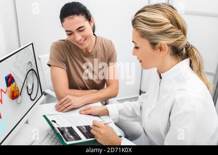 Kardiologe während einer Konsultation, die dem Patienten einen Ultraschall ihres Herzens zeigt, sind die Ergebnisse der Sonographie einer Untersuchung des weiblichen Herzens sehr Stockfoto