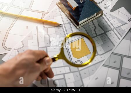 Baugrundstück für Familienhausbau suchen - Hand mit Lupe auf Katasterkarte Stockfoto