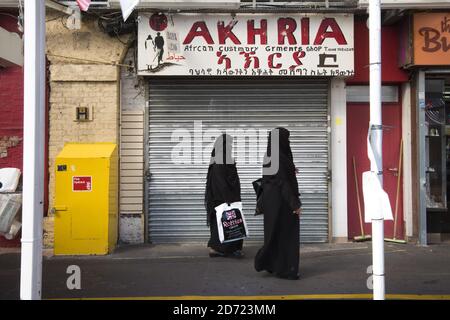 Zwei muslimische Frauen gehen an einem afrikanischen Bekleidungsgeschäft in Shepherd's Bush Market im Westen Londons vorbei. Der Markt verkauft eine multikulturelle Mischung aus indischen, polnischen, afrikanischen und karibischen Waren. Am 30. September wird es 100 Tage her sein, seit das Vereinigte Königreich für den Austritt aus der EU gestimmt hat, in denen die gemeldeten Hassverbrechen gegen Immigranten zugenommen haben. Stockfoto