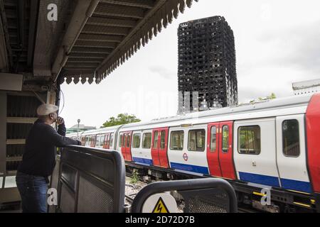 Ein U-Bahn-Zug fährt an den Überresten des Grenfell Tower vorbei, einen Monat nachdem das Feuer den 24-stöckigen Block in Kensington, London, verschlang. Bilddatum: Mittwoch, 12. Juli 2017. Bildnachweis sollte lauten: Matt Crossick/ EMPICS Entertainment. Stockfoto