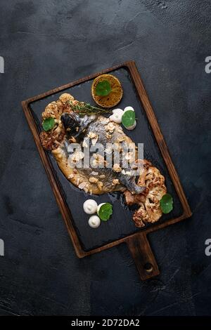 Fischgerichte Kochvorbereitung mit dorado in Rückenform in Form von Fisch mit gesundem Gemüse auf dunklem rustikalem Hintergrund mit Zutaten, top Stockfoto