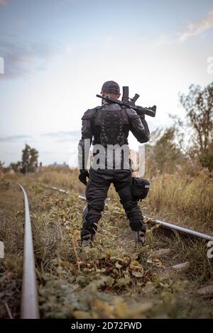 Ein Mann mit einem Gewehr in Uniform steht mit seinem Zurück Stockfoto