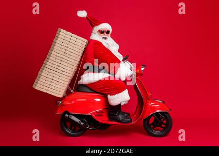In voller Länge Profil Foto von im Ruhestand Opa weißen Bart reiten Vintage Moped Pizza Boxen weihnachten Charity Lieferung tragen santa Weihnachten Kostümmantel Stockfoto