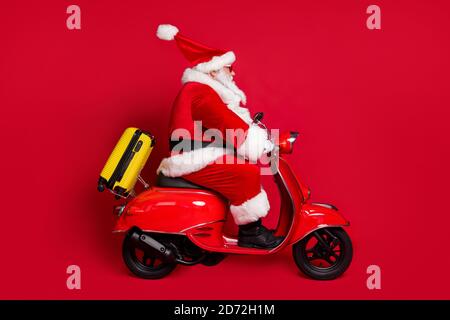 Beeilen Sie sich im Urlaub. In voller Länge Profil Foto von im Ruhestand Opa weißen Bart Fahrt schnell vintage Moped Tasche frei Wochenende tragen santa Weihnachten Kostüm Mantel Stockfoto