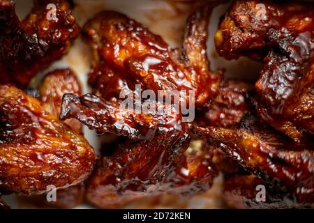 Nahaufnahme von Chicken Wings in dicker Grillsoße. Serviert auf einer weißen gusseisernen Schüssel Stockfoto