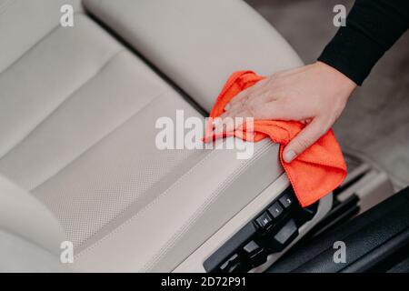 Nahaufnahme von mans Hand wischt Autositz mit Mikrofaser Tuch. Automatisches Reinigungskonzept. Waschsalon. Wischstaub Stockfoto