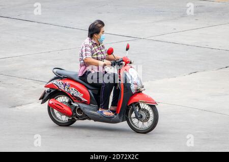 SAMUT PRAKAN, THAILAND, JULI 25 2020, Frau mit Gesichtsmaske fährt ein Motorrad Stockfoto