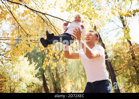 Vater hält seine Tochter in den Händen und haben Spaß in Der Herbstpark Stockfoto