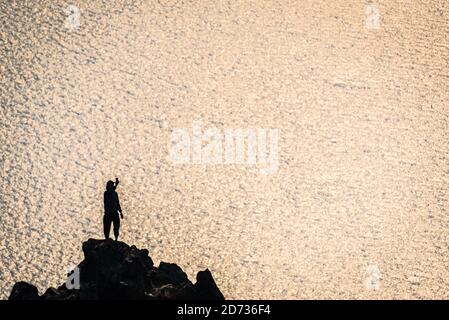 Der Mensch ist wie ein Schattenbild, wenn er ein Selfie über dem Crater Lake macht, während der Waldbrand die Atmosphäre im Crater Lake National Park, Oregon, USA, verdunkelt. Stockfoto