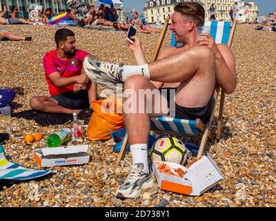 BRIGHTON, GROSSBRITANNIEN - 2. JUNI: Frank (ganz rechts), der als Gerüstbauer arbeitet, genießt Fisch und Chips und ein Bier mit Freund Adam am Brighton Beach. Stockfoto