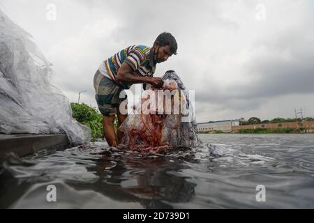 Ein Mann aus Bangladesch wäscht Plastikmüll, der zum Transport von Chemikalien verwendet wurde, im Wasser des Turag-Flusses, bevor er ihn recycelt, in Tongi, in der Nähe von Dhaka, Stockfoto