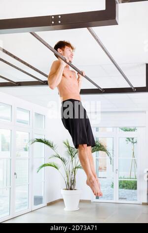 Mann, der kalisthenetische Übungen macht, zieht sich an einer Stange hoch Mit den Armen zu stärken seine Muskeln in einem hohen Key Gym in einem Gesundheits-und Fitness-concep Stockfoto
