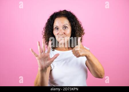 Frau mittleren Alters trägt lässige weiße Hemd stehend über isoliert Rosa Hintergrund zeigt und zeigt nach oben mit den Fingern Nummer sechs Beim Lächeln confi Stockfoto