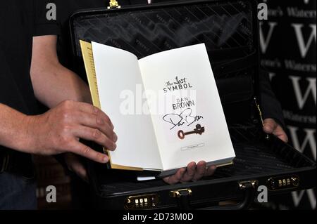 Sicherheitskräfte von Transworld Publishing übergeben das erste Exemplar von Dan Browns neuestem Buch, The Lost Symbol, an Waterstones Mitarbeiter Jon Howells in ihrem Piccadilly-Laden in London. Howells wird die erste Person in Großbritannien sein, die das Buch liest und es über Nacht liest, bevor es morgen früh um 7 Uhr in den Verkauf geht. Bilddatum: 14. September 2009. Stockfoto