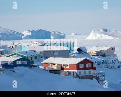 Meereis in der gefrorenen Disko Bay mit Eisbergen. Stadt Ilulissat am Ufer der Disko Bay in Westgrönland, Zentrum für Tourismus, Verwaltung und eg Stockfoto